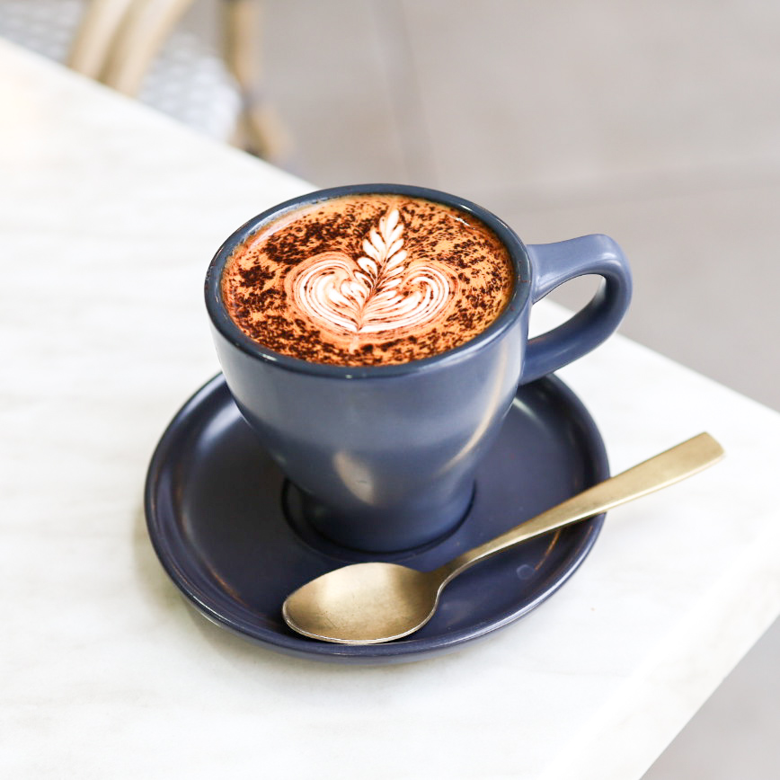 Mocha with feather latte art in Ariel's signature navy cup