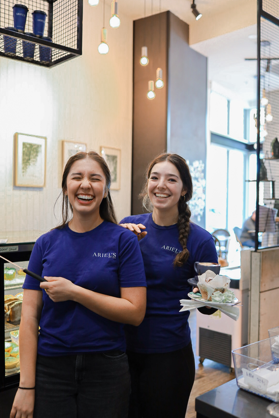 Two Ariel's Coffee team members smiling together in the café