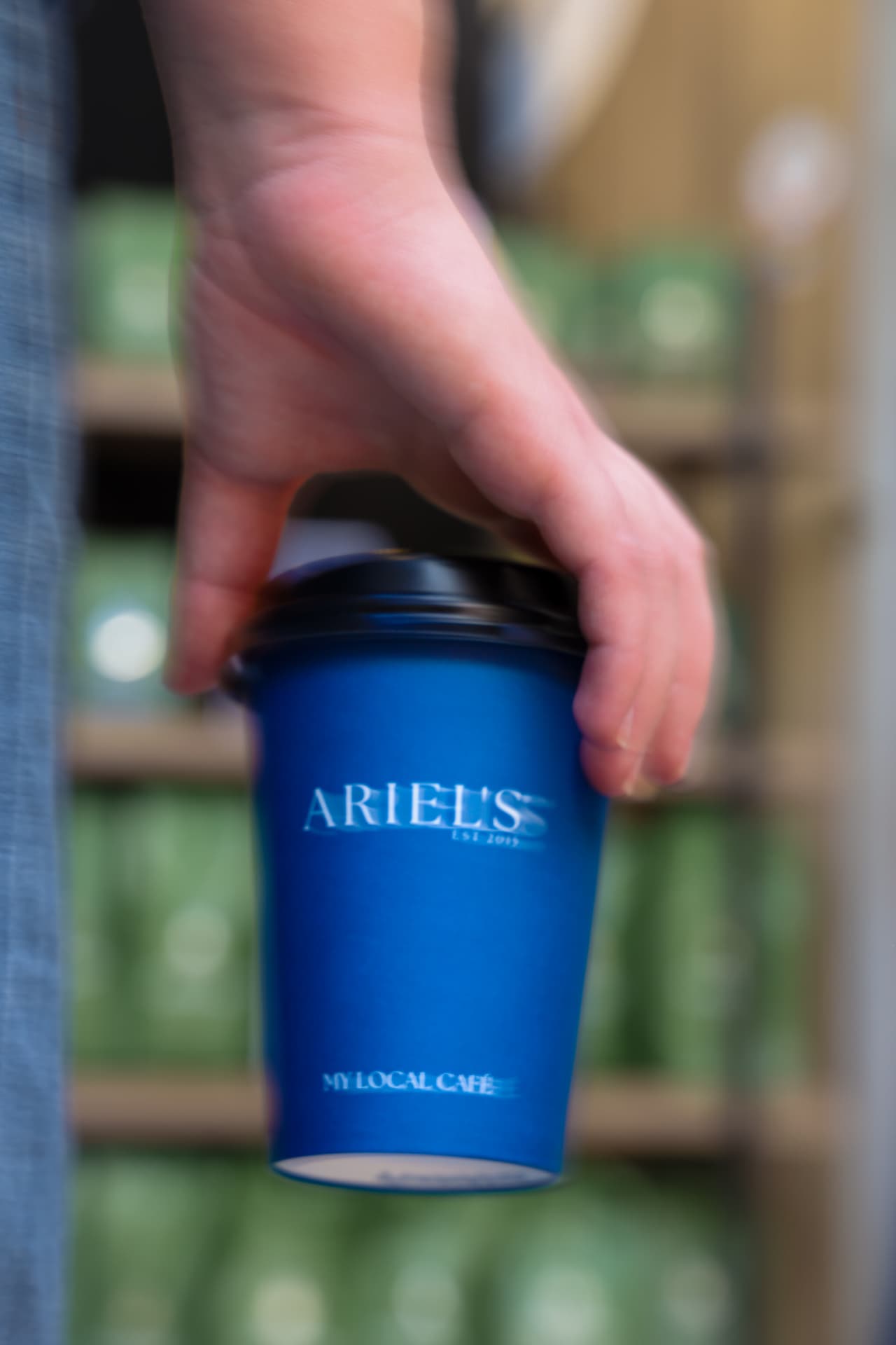 Ariel's navy takeaway coffee cup held in hand