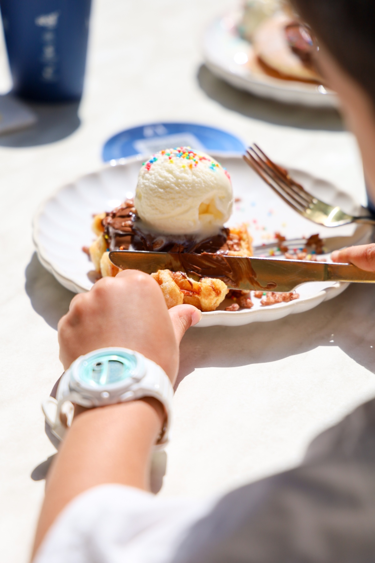 Child tucking into a waffle with ice cream