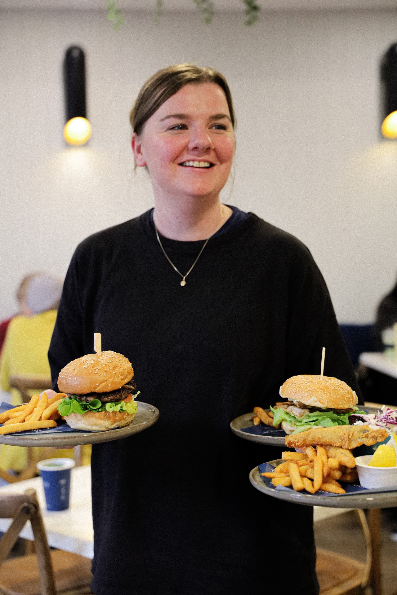 Ariel's team member carrying burger and fish plates