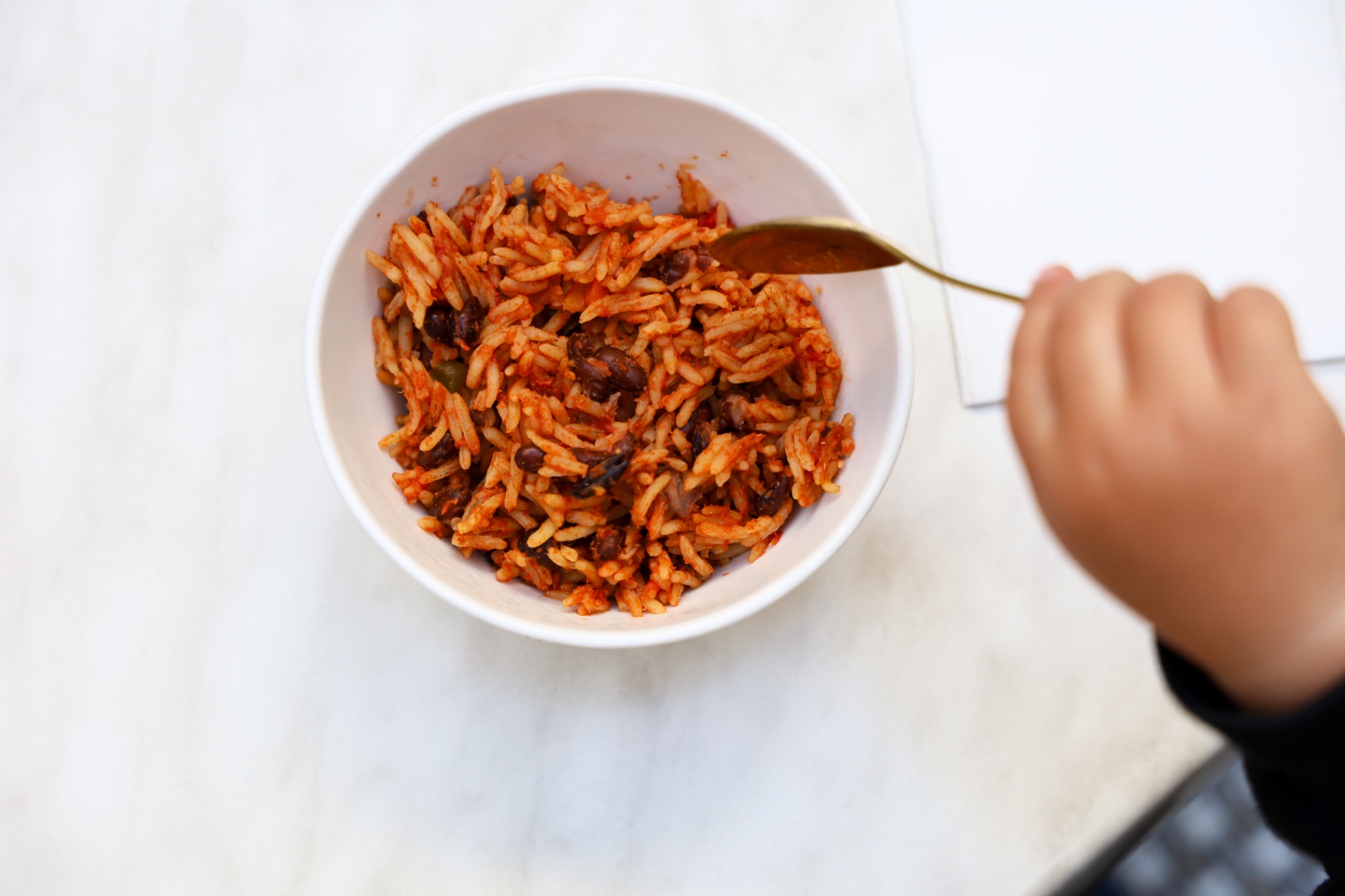 Little hand with a spoon and a bowl of rice