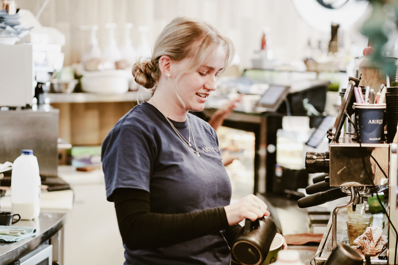 Barista steaming and pouring milk at the espresso machine