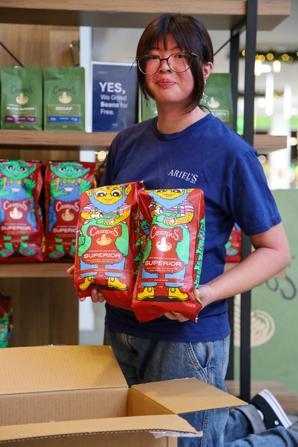 Ariel's barista holding bags of Campos Superior coffee beans
